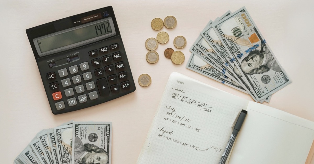 Person writing a monthly budget plan in a notebook at a clean desk with a coffee cup nearby