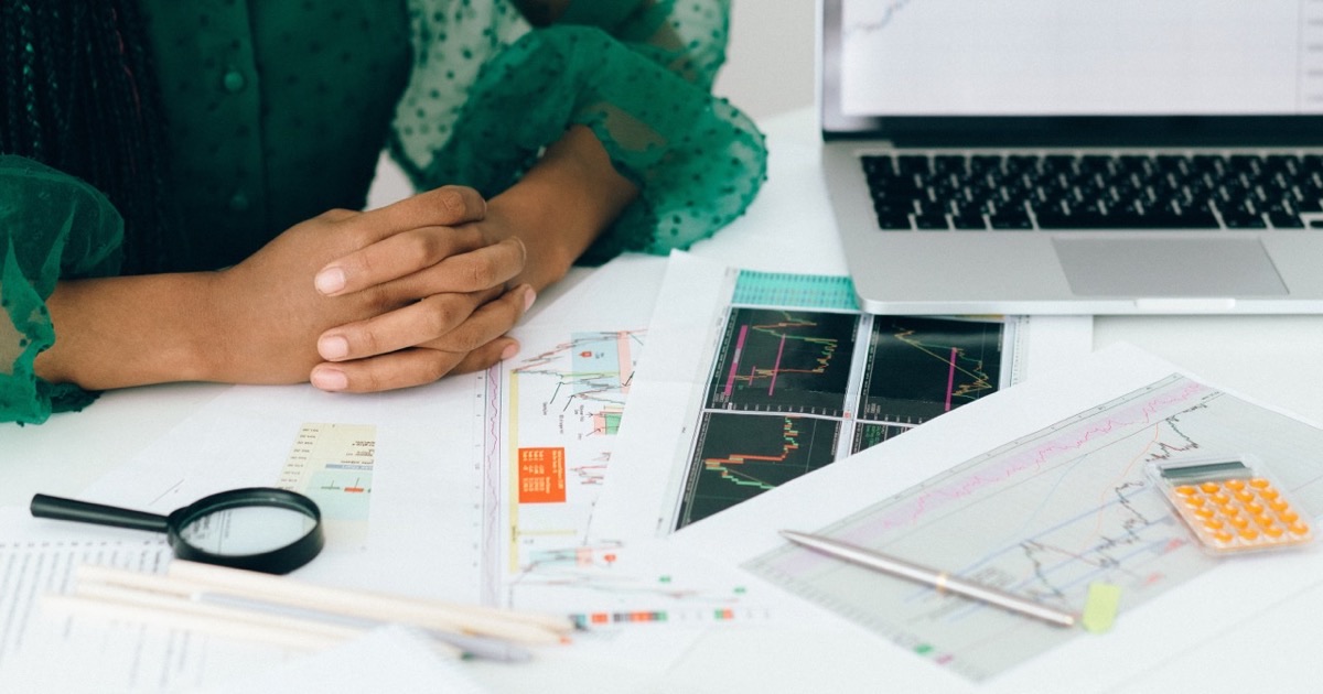 Person reviewing break-even analysis documents at a bright white desk with a pen