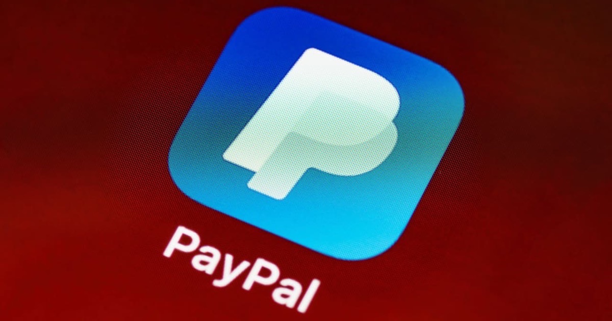 Person reviewing a printed PayPal transaction on a clean desk with a pen