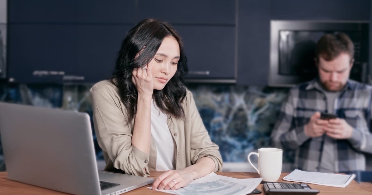 Person reviewing urgent financial documents calmly at a kitchen table with warm side light