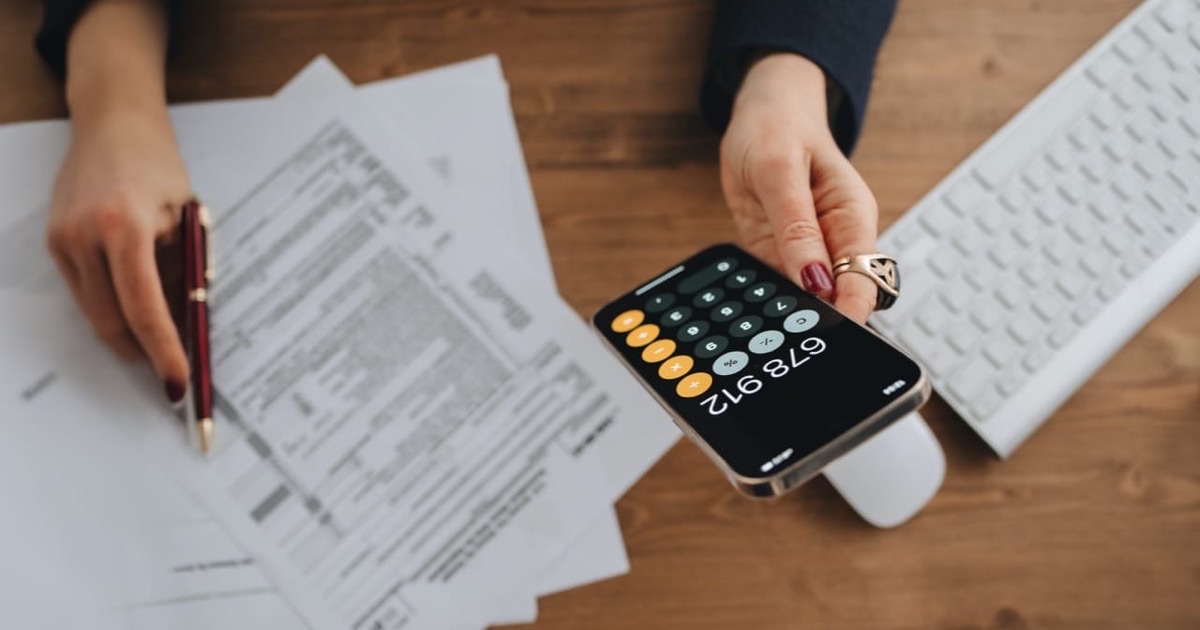 Person tracking monthly expenses in a colorful budgeting notebook at a bright modern desk